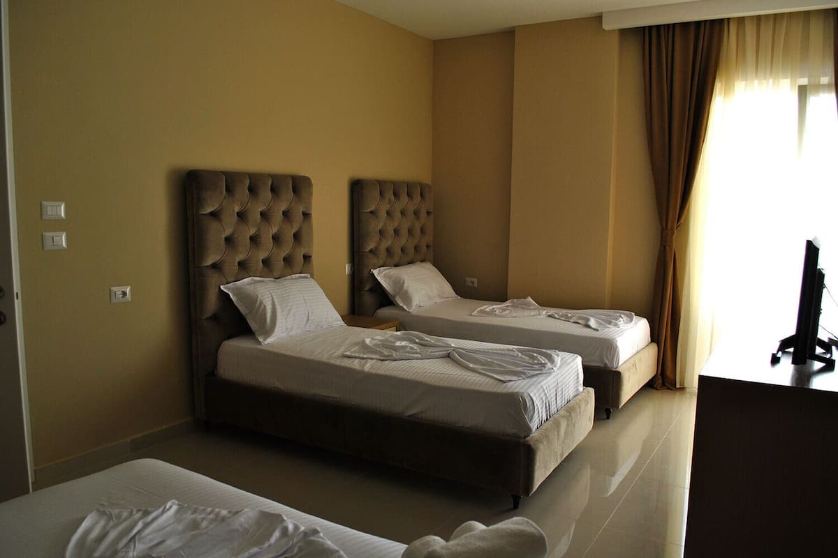 Ein Hotelzimmer mit zwei Betten, einem Fernseher und einem Schreibtisch.