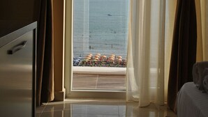 Un cuarto de hotel con vista al mar, un balcón con sombrillas y una cama.