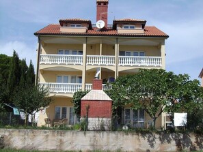 Stunning multi-story building with a central chimney and balcony on each floor, set amidst lush greenery.