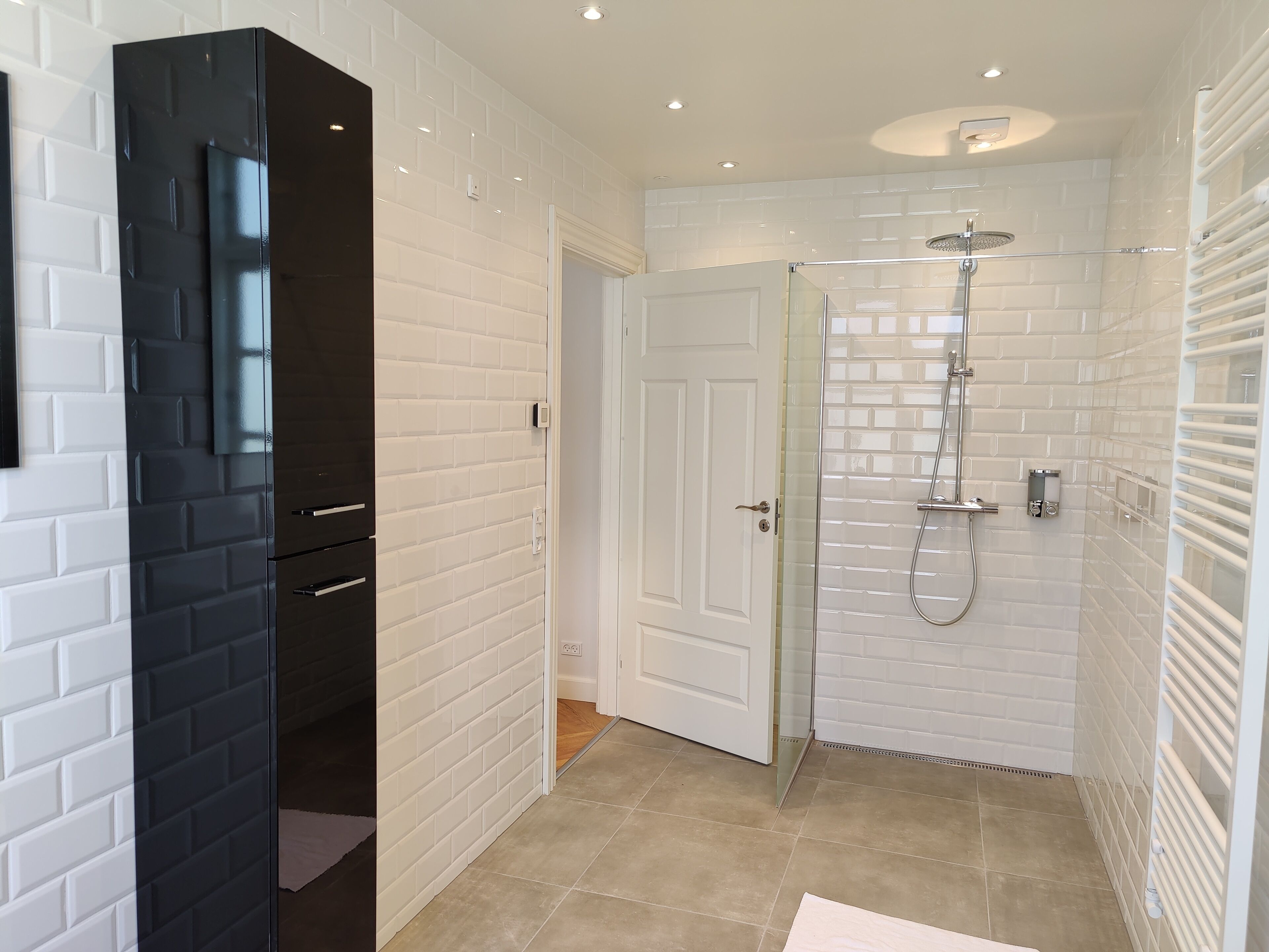 A modern bathroom with white brick walls, a glass-enclosed shower, and a black cabinet.