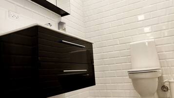 Ein modernes Badezimmer mit weißen Fliesen, einem schwarzen Waschtisch und einer weißen Toilette.