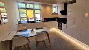 Una cocina moderna con armarios blancos, encimera negra y un comedor con mesa y sillas.
