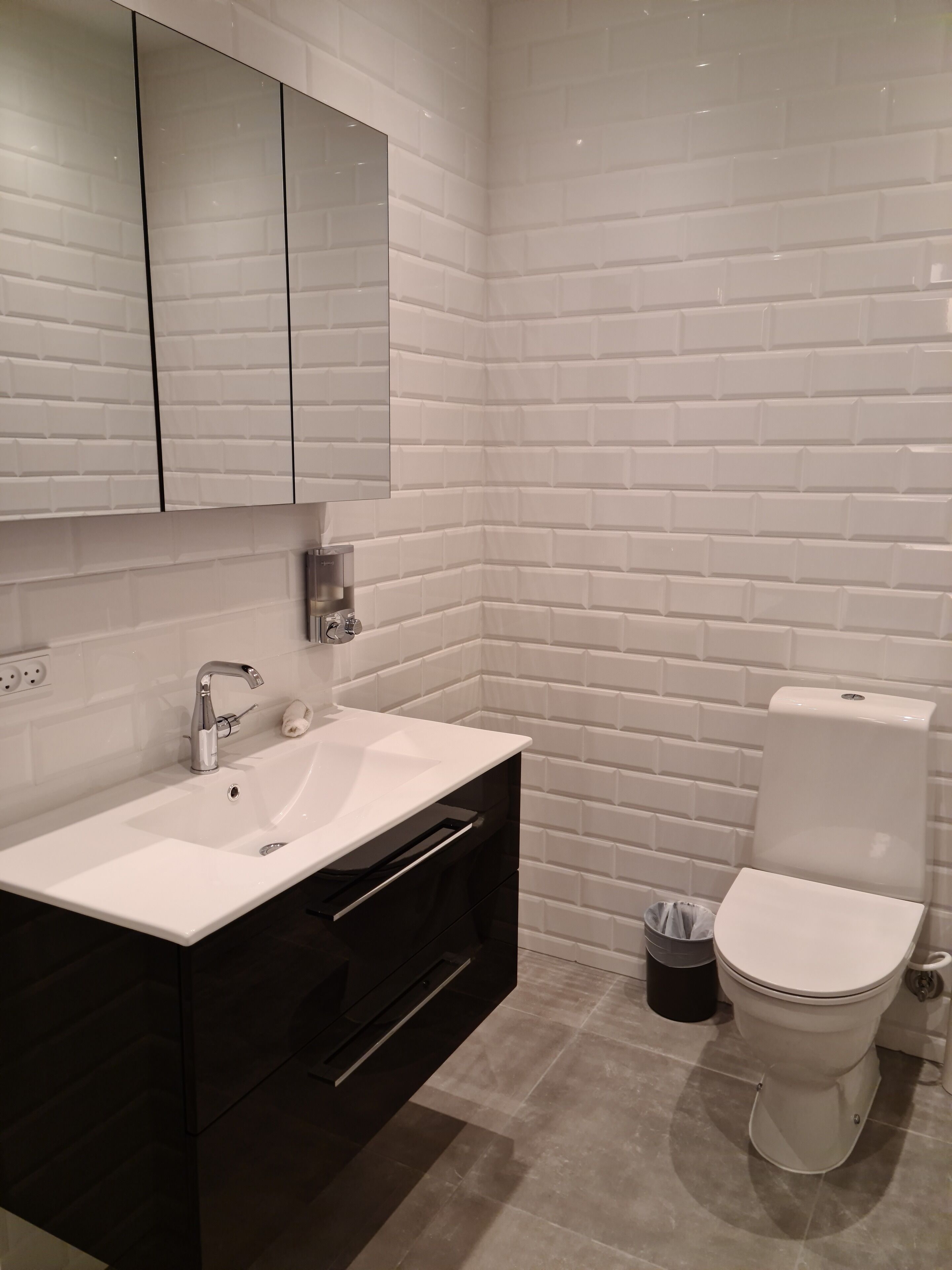 A modern bathroom with a white sink, black vanity, and a white toilet.