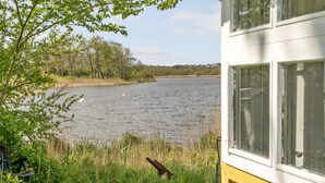 Vista sobre un lago con un edificio parcialmente visible, que incluye una ventana y un banco.