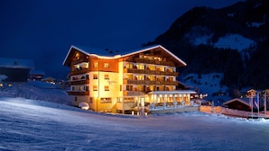 A multi-story hotel with balconies, located in a snowy mountainous area. - Hotel Roslehen (Grossarl)