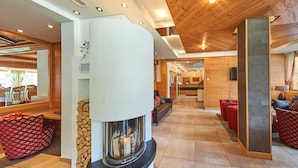 A modern interior with a fireplace, wooden ceiling, and cozy seating areas. - Hotel Roslehen (Grossarl)