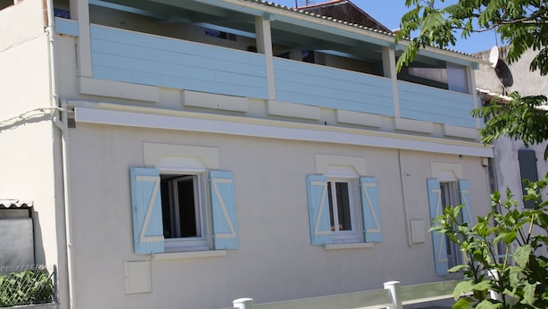 Ein zweistöckiges Gebäude mit hellblauen Fensterläden und einem Balkon.