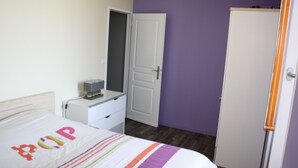 Ein Schlafzimmer mit Bett, Kommode, Kleiderschrank und einer Tür.