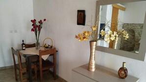 A dining area with a table, chairs, a vase with flowers, a mirror, and a bottle on a dresser. - Central Hotel (Parga)