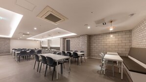 A spacious conference room with multiple tables and chairs, a brick accent wall, and recessed lighting. - Cheonan Brown Dot Hotel Cheonan Station (Cheonan)
