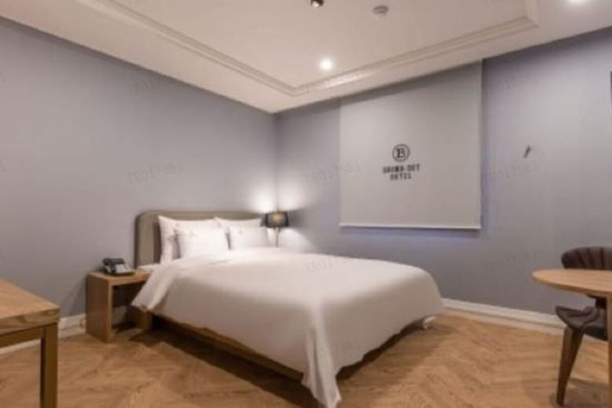 Un dormitorio con una cama grande, una mesita de noche y una lámpara de pared.