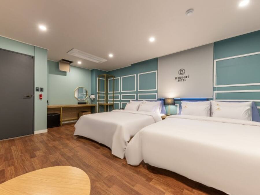 A hotel room with two beds, a desk, a mirror, and a wall-mounted sign.