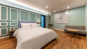 A hotel room with a large bed, a seating area with a patterned sofa, and a wall-mounted TV. - Cheonan Brown Dot Hotel Cheonan Station (Cheonan)