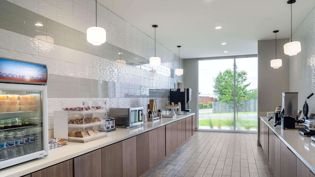 Una cocina moderna con un refrigerador empotrado, una cafetera y una vitrina con pasteles.