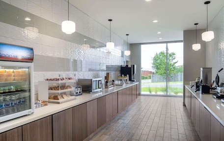 A modern kitchen with a built-in refrigerator, a coffee machine, and a display case with pastries.