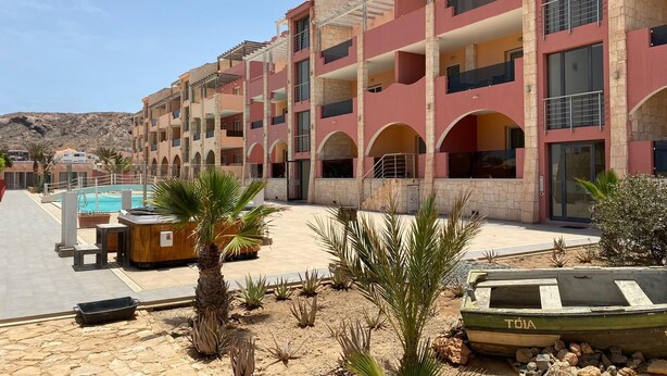 A multi-story hotel with a pool area, palm trees, and a boat. - PORT DO SOL - free wifi NO LIMITS (Contea di Boa Vista)