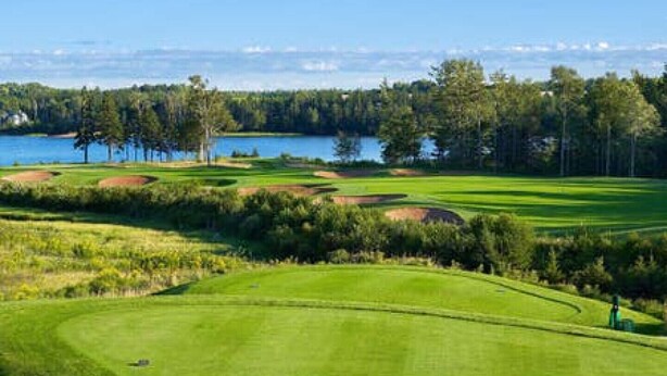 A golf course with bunkers, a water body, and a forested area. - One-minute walk to a sandy beach. Beachside Haven Cottage awaits. (Belle River)