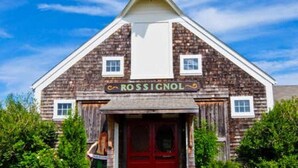 A rustic wooden building with a sign reading "ROSSIGNOL." - One-minute walk to a sandy beach. Beachside Haven Cottage awaits. (Belle River)