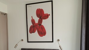 Ein Schlafzimmer mit einer gesteppten Kopfteil, einem Bett mit floralem Bettzeug, einem gerahmten Kunstwerk mit roten Ballons und Nachttischlampen.