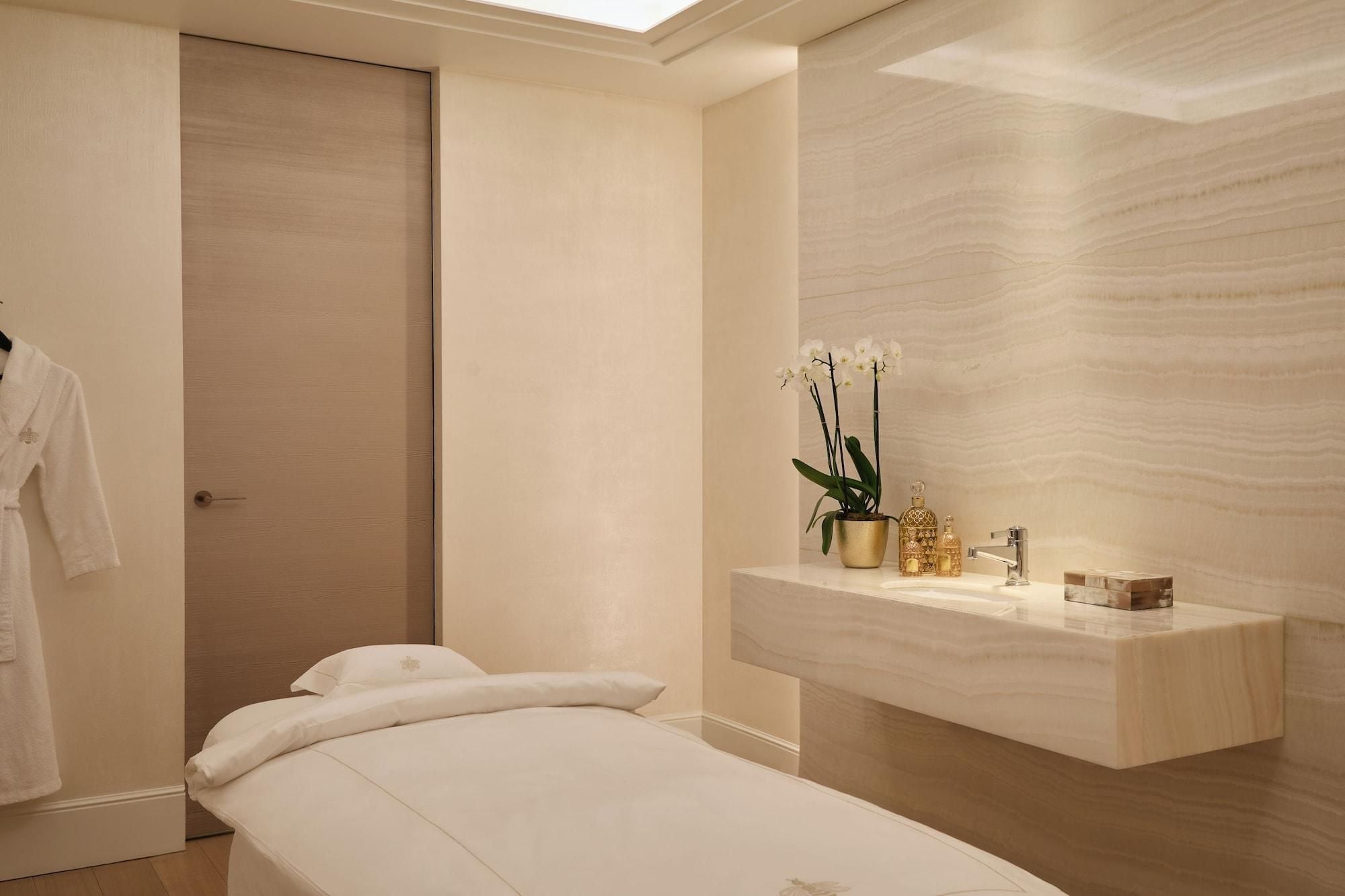 Une chambre à coucher moderne, comprenant un lit, une table de chevet, un miroir et une petite salle de bain avec un lavabo et des objets décoratifs.