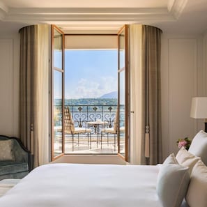 A hotel room with a large bed, a view of a balcony with outdoor furniture, and curtains on the windows. - The Woodward An Oetker Collection Hotel (Geneva)
