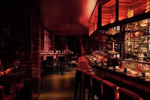 A dimly lit bar area with wooden paneling and a long counter. - The Woodward An Oetker Collection Hotel (Geneva)