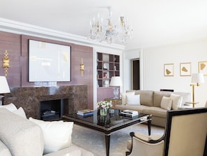 A modern living room with a fireplace, a sofa, a coffee table, and a chandelier. - The Woodward An Oetker Collection Hotel (Geneva)