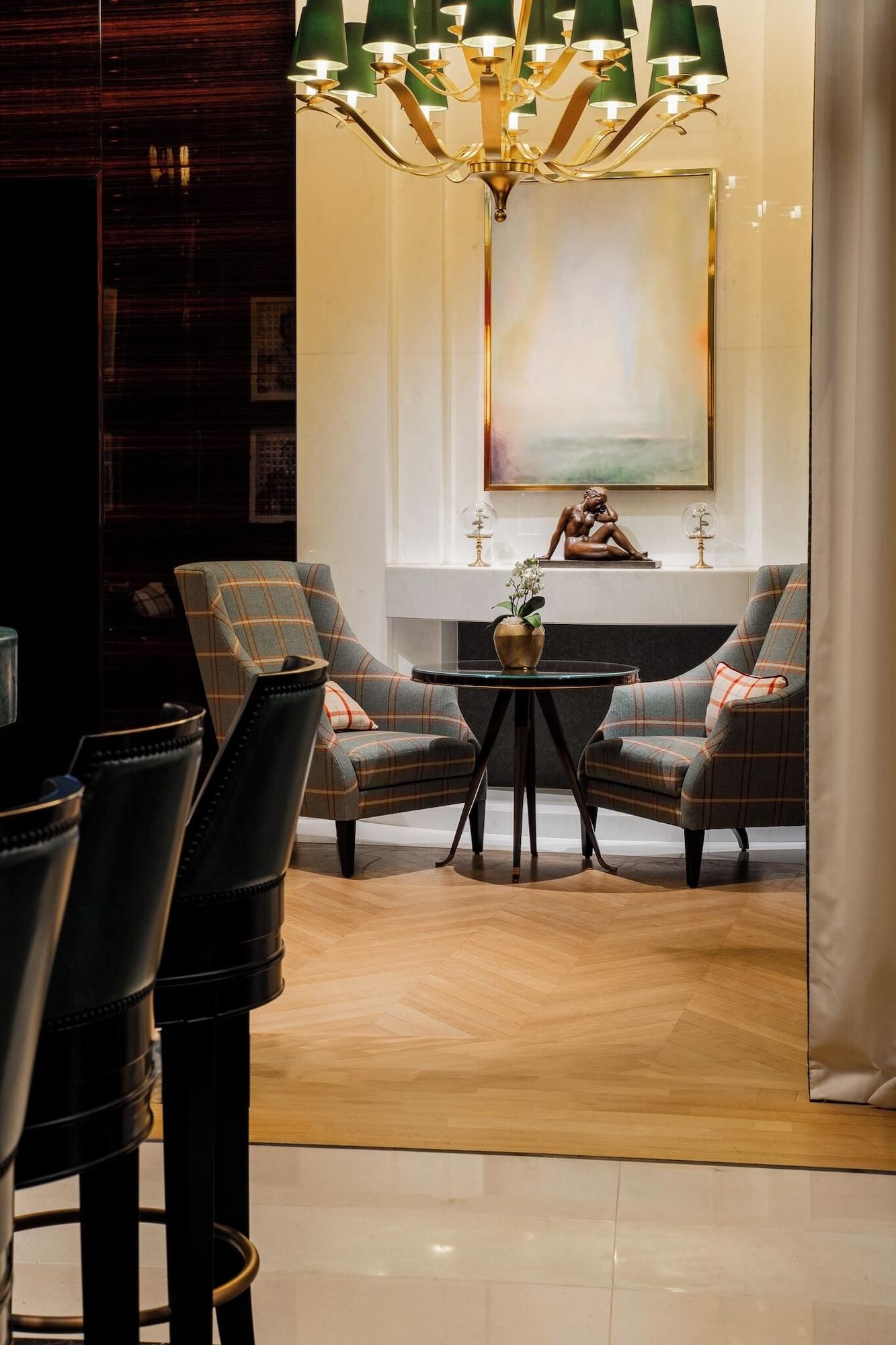 A modern living room with two plaid armchairs, a small round table, and a chandelier.