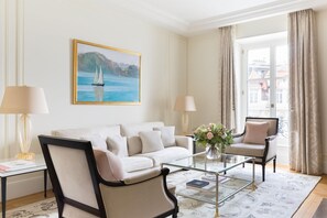 A modern living room with a sofa, armchairs, a glass coffee table, and a painting of a sailboat on the wall. - The Woodward An Oetker Collection Hotel (Geneva)