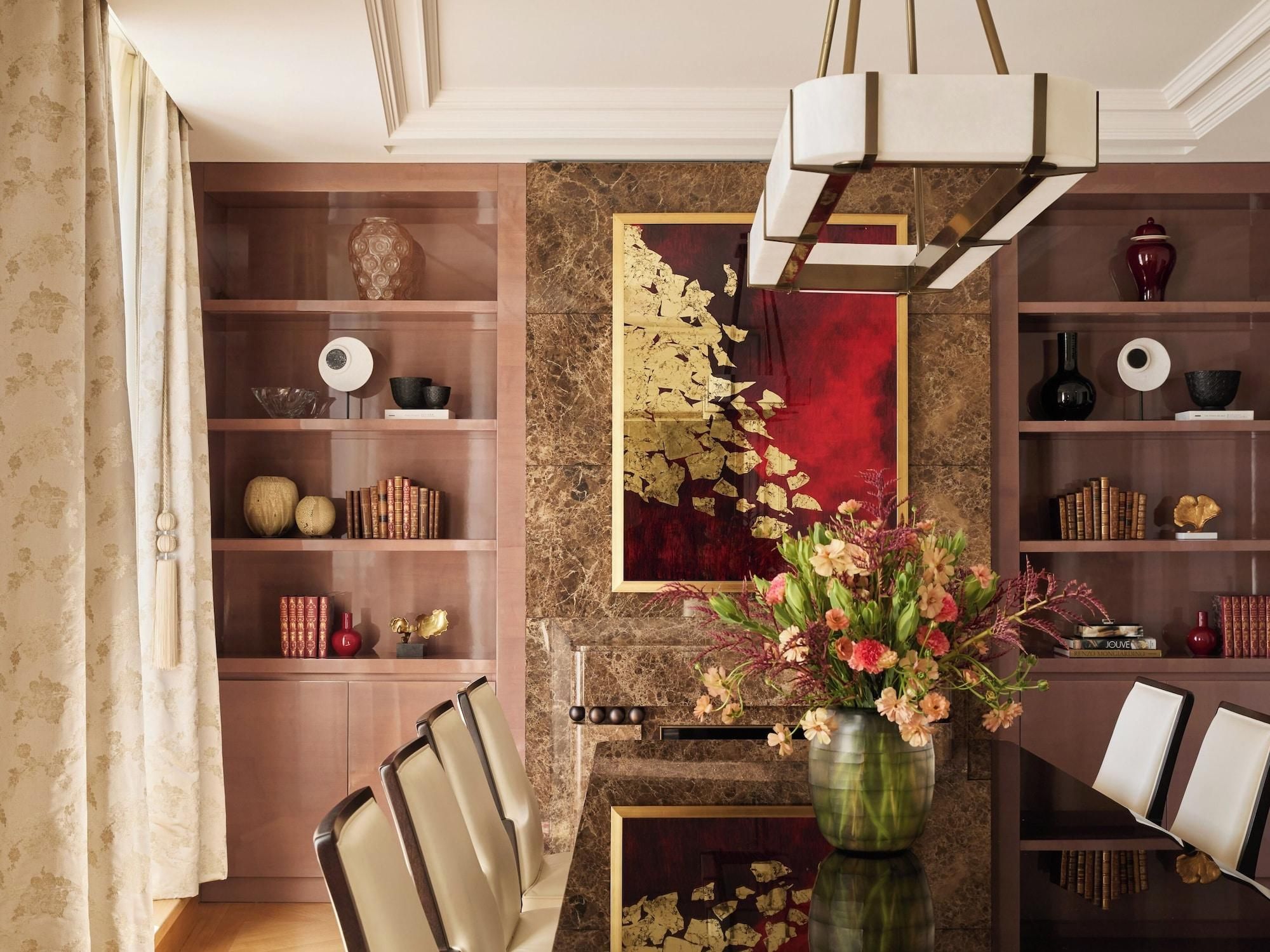A dining area with a marble wall, a chandelier, and a vase of flowers.