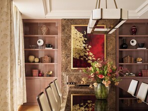 A dining area with a marble wall, a chandelier, and a vase of flowers. - The Woodward An Oetker Collection Hotel (Geneva)