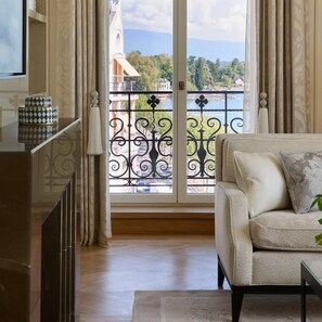 A living room with a sofa, a small table, and a view of a balcony with a railing. - The Woodward An Oetker Collection Hotel (Geneva)