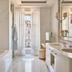 A modern bathroom with marble flooring, a double sink vanity, a large mirror, and a view through a window with curtains. - The Woodward An Oetker Collection Hotel (Geneva)