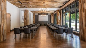 A conference room with wooden panel ceilings, a chandelier, and a large screen at the front.