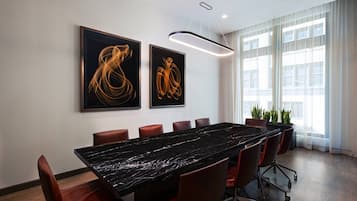 A conference room with a long table, red chairs, and two abstract paintings on the wall.