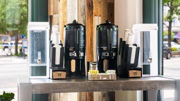 Une machine à café équipée de plusieurs modules de préparation, une petite plante et un fond en bois.