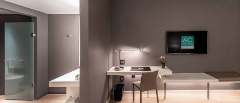 Una habitación de hotel moderna con escritorio, silla y televisor de pantalla plana montado en la pared.