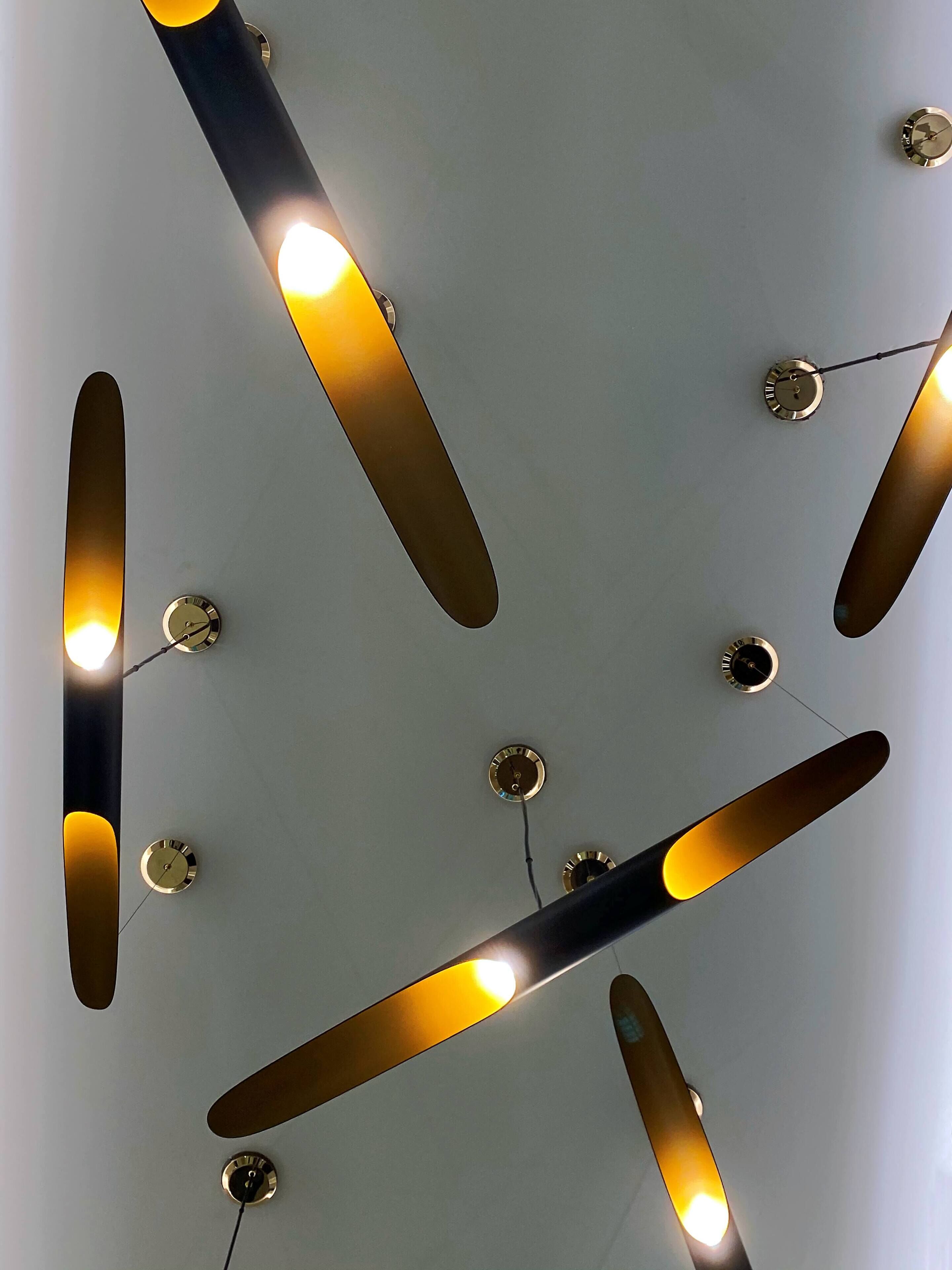 A ceiling with multiple light fixtures and wall-mounted clocks.