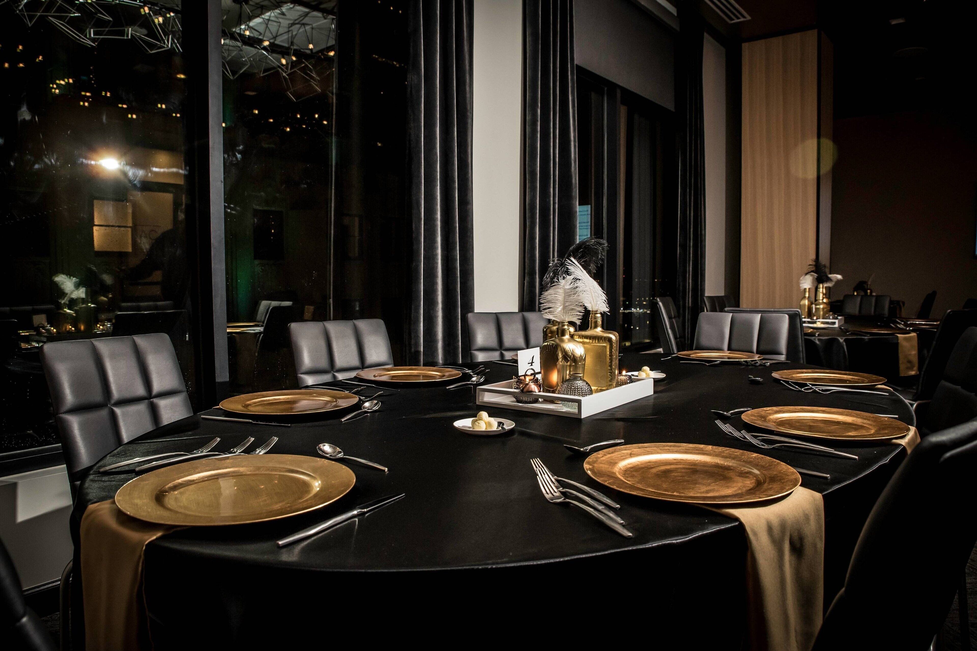 A dining table set for a meal with gold plates, silverware, and a centerpiece.