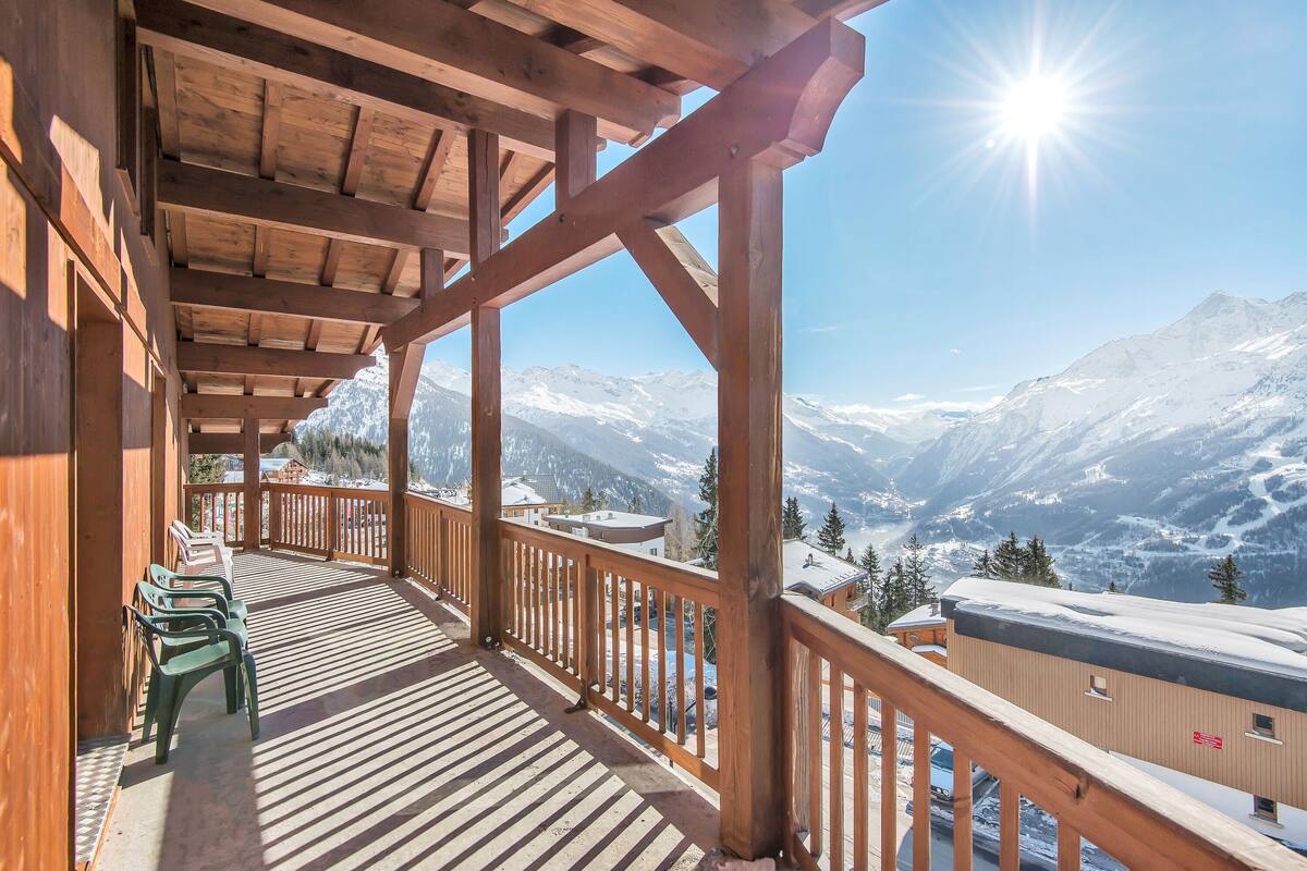 Un balcón de madera con vistas a montañas nevadas.