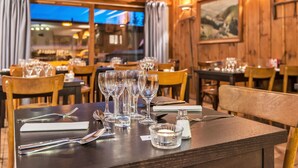 Un restaurante con paredes de madera, mesas dispuestas con copas de vino, cubiertos y servilletas.
