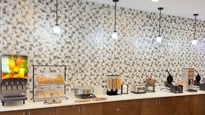 Una barra de desayuno con cafetera, máquina para gofres, tostadora y diferentes alimentos.