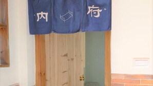 A wooden door with a blue curtain, a brick wall, and a tiled floor. - O! Share Sweet B&B II (Jinning)