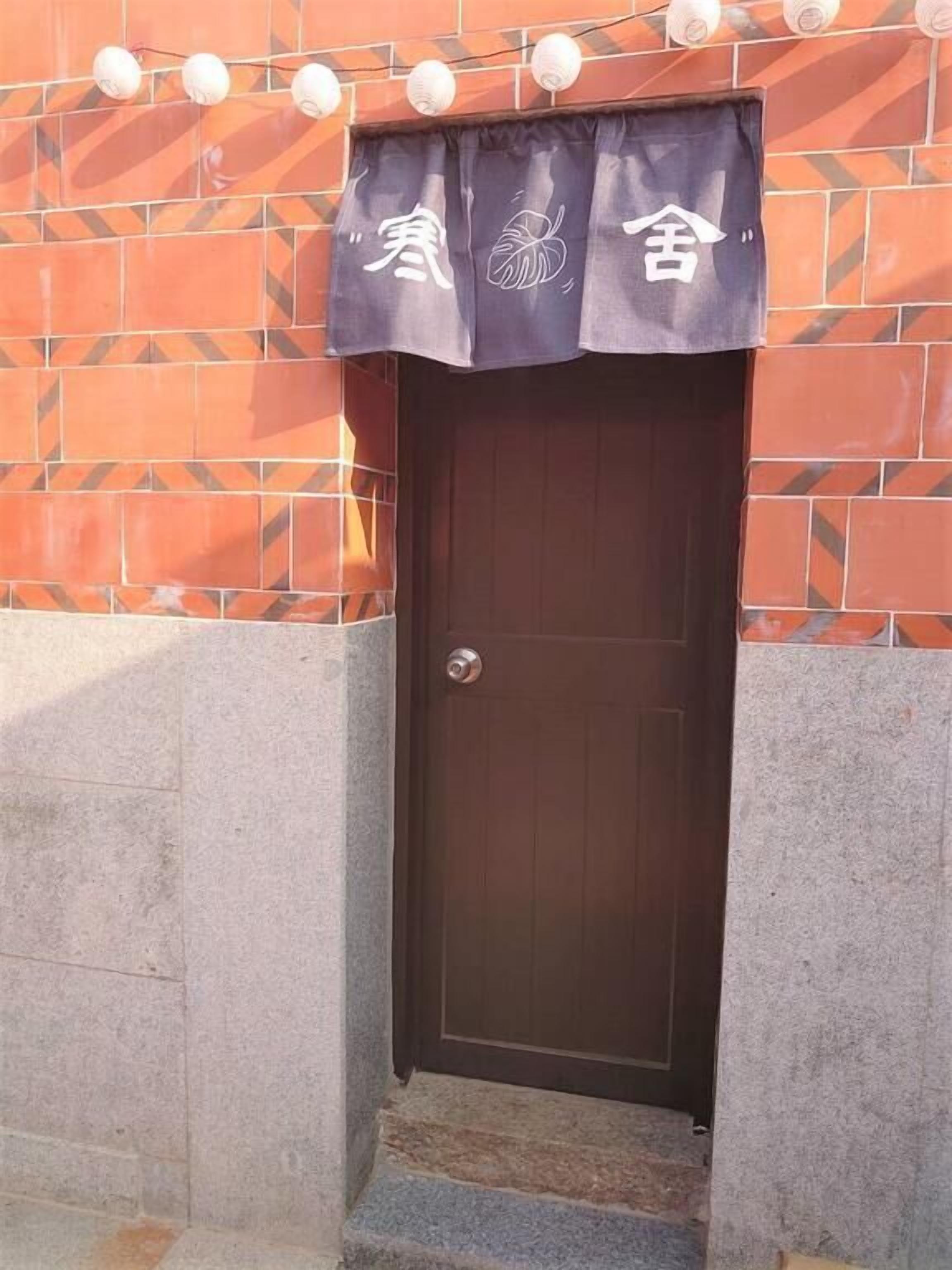 A door with a dark brown color, a metal handle, and a decorative curtain with white text and a leaf design.