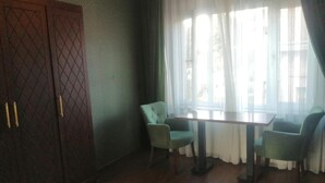 A room with a wooden wardrobe, a round rug, and a table with two chairs.