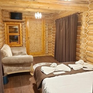 A cozy log cabin room with a bed, a chair, a small table with towels, a wooden door, and a window. - Park Beylerbeyi Boutique Hotel (Istanbul)