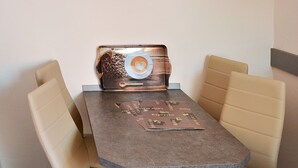 Una zona de dinar petita amb una taula i quatre cadires, un rellotge decoratiu a la paret i un suport per als menús.