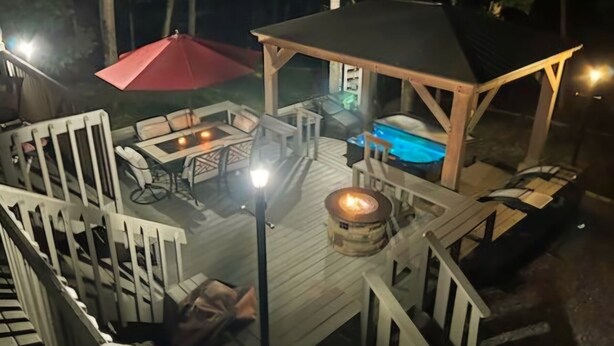 Una terraza de madera con mobiliario exterior, un jacuzzi y una zona de estar techada.