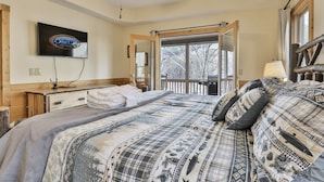 A bedroom with a bed, a television, a wooden dresser, a window, and a balcony. - Tie One On The River | Ellijay, GA (Ellijay)