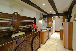 A kitchen with wooden cabinetry, a central island, and a stainless steel range hood.